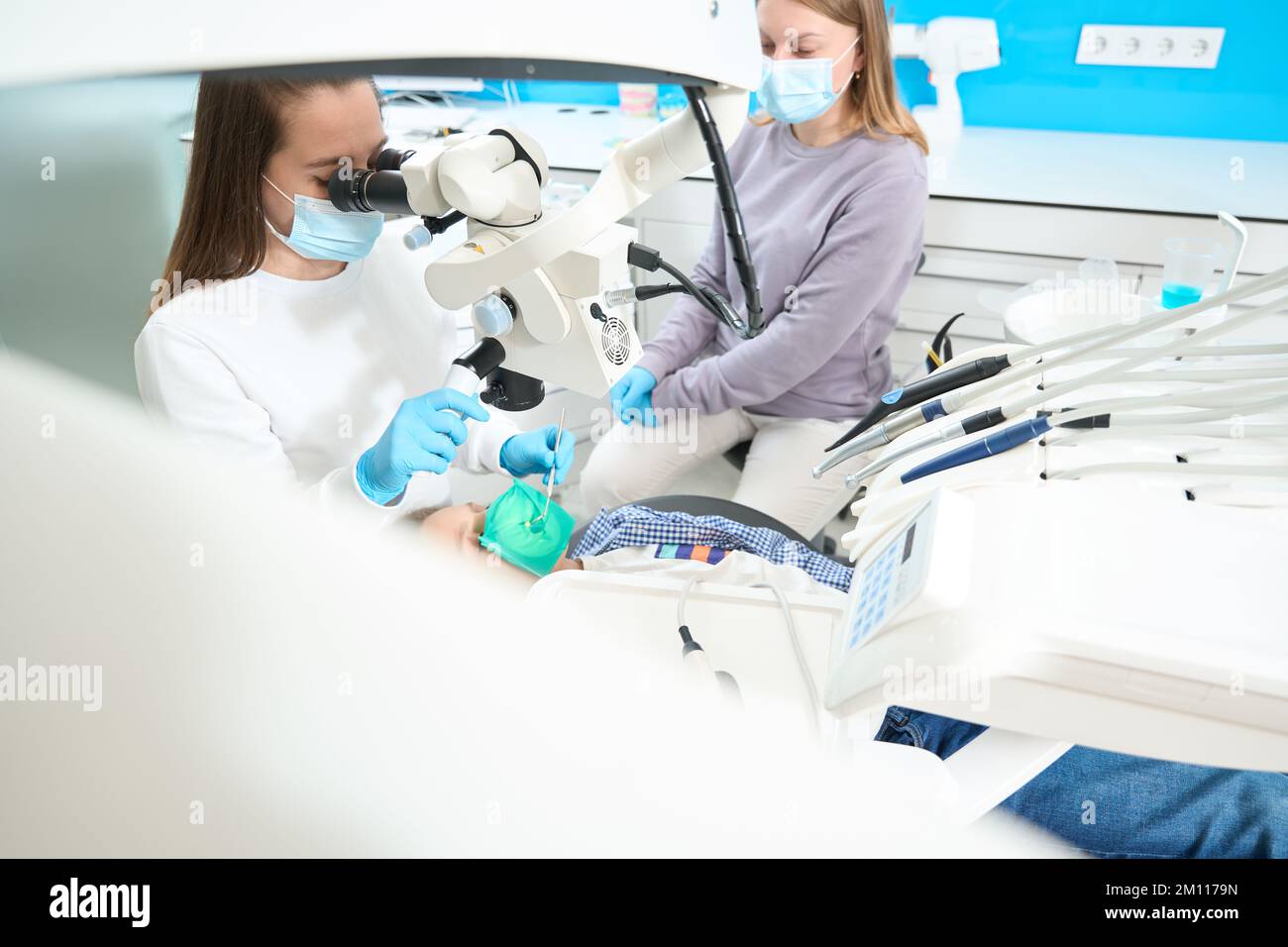 Root canal treatment for child in modern dental clinic under microscope