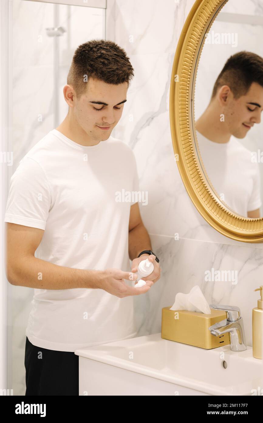 Man use shaving foam at bath. Handsome male in white t-shirt. First fime shaving Stock Photo