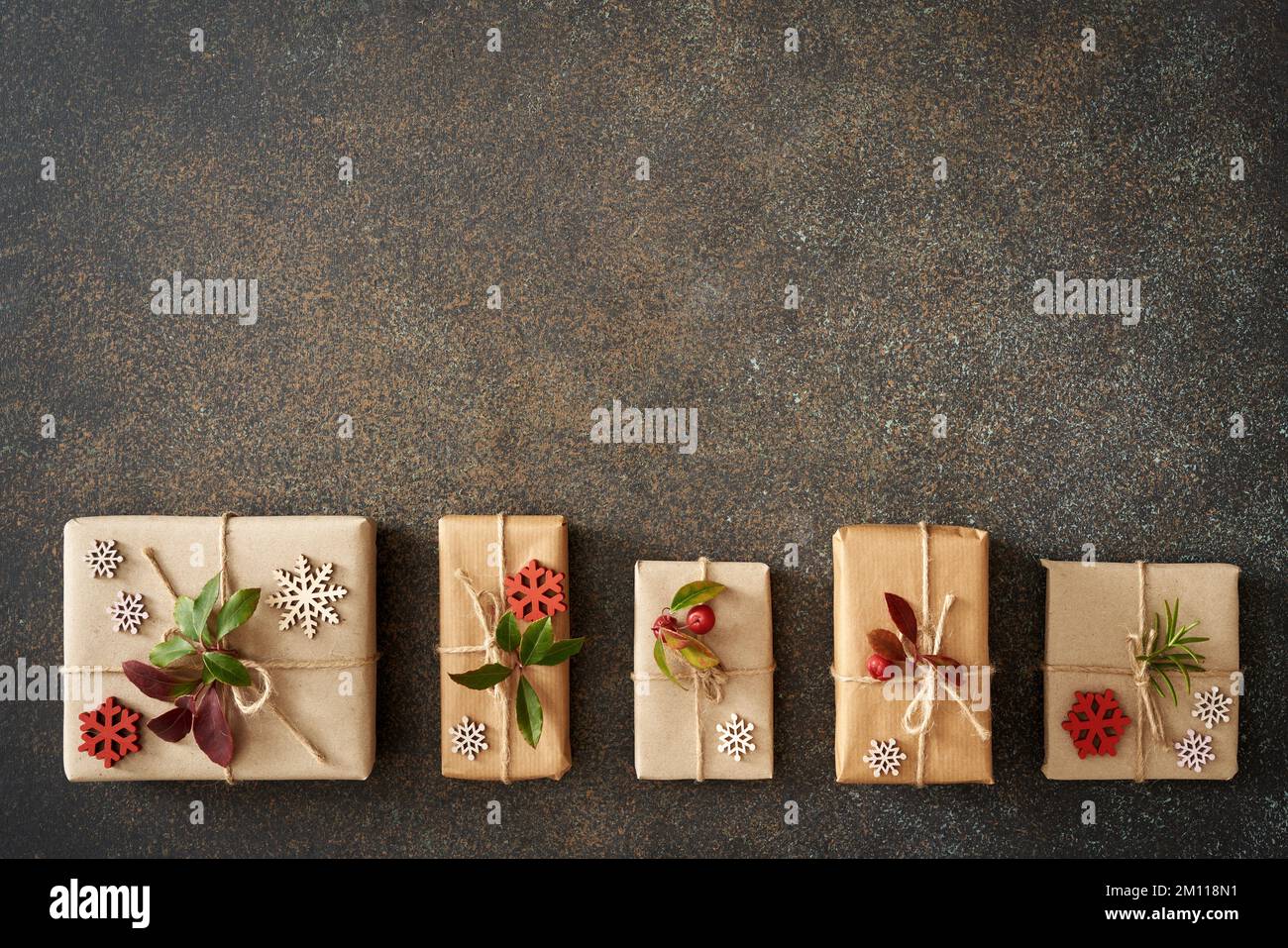 Christmas present wrapped in ecological recycled paper with wintergreen twigs on dark background with copy space Stock Photo