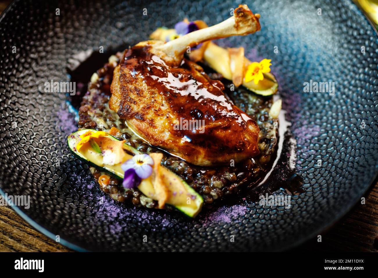 Corn chicken supreme. Beluga lentils, Old Ammerlander cheese, mini zucchini, red wine sauce. Delicious healthy traditional food closeup served for Stock Photo