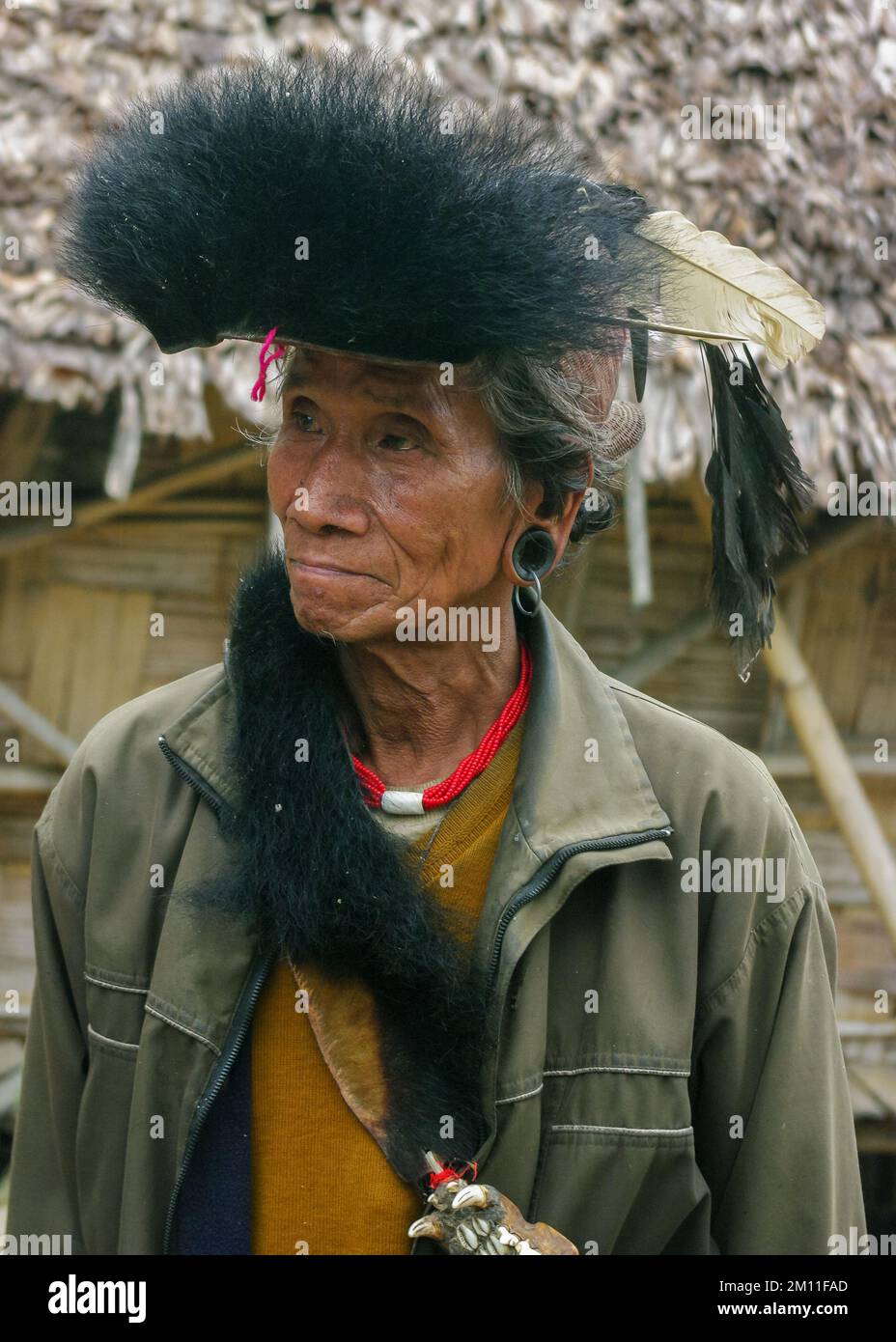 Raga, Arunachal Pradesh, India - 11 14 2010 : Portrait of Nyishi tribe shaman wearing machete knife and traditional headgear with feathers and fur Stock Photo