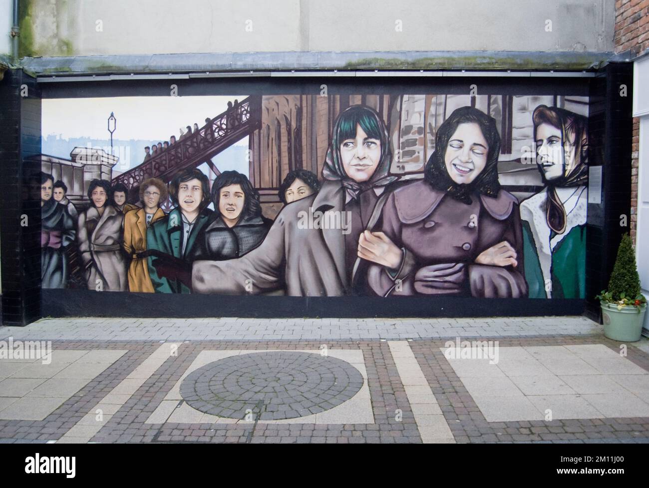 Ireland, North, Derry City, Murals depicting the original Derry Girls who worked in shirt making factories in The Craft Village within the old city walls. Stock Photo