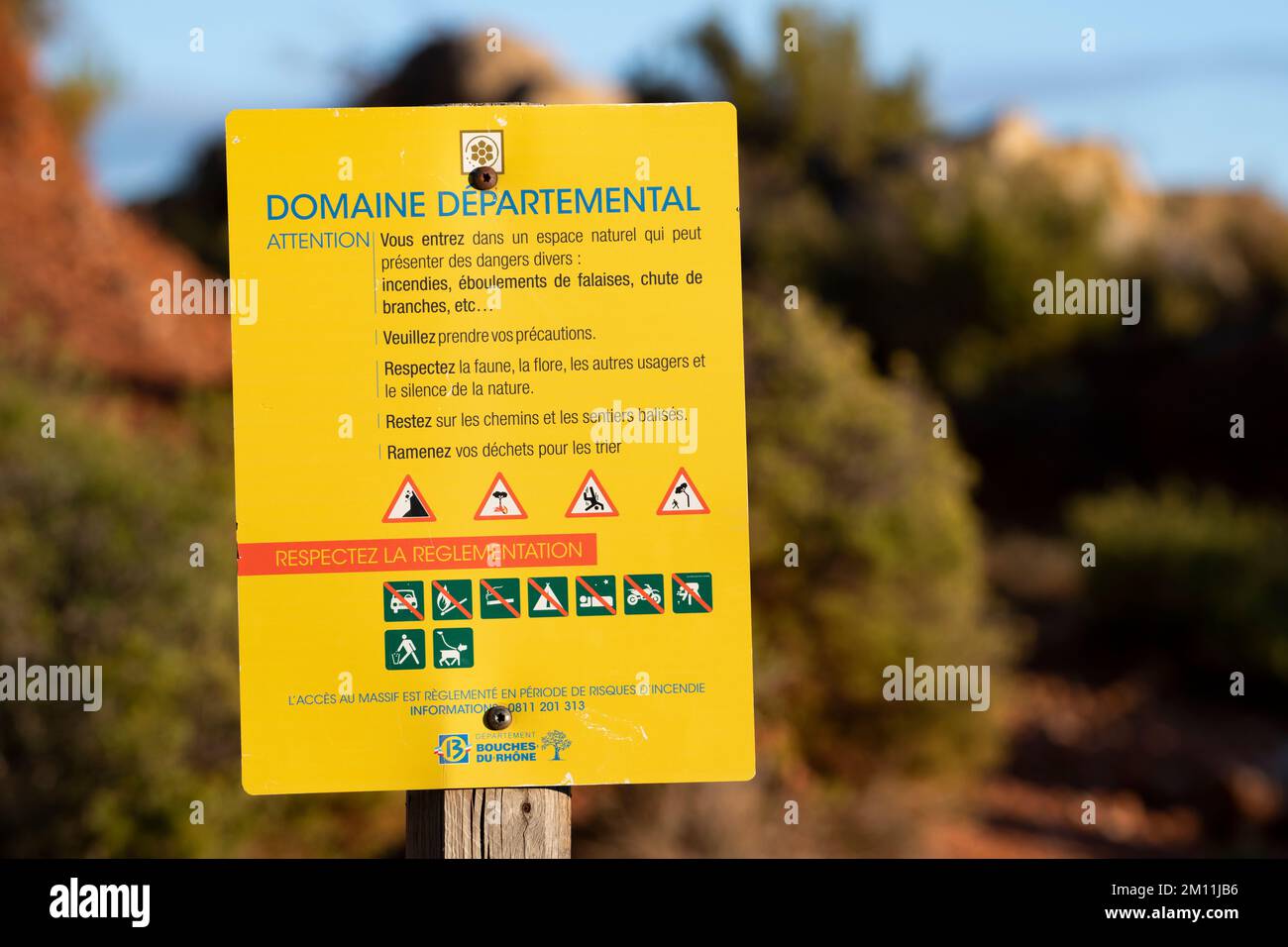 Yellow Sign with a red and white French text in the forest in the South of France to indicate a Departmental Domain and rules to follow Stock Photo