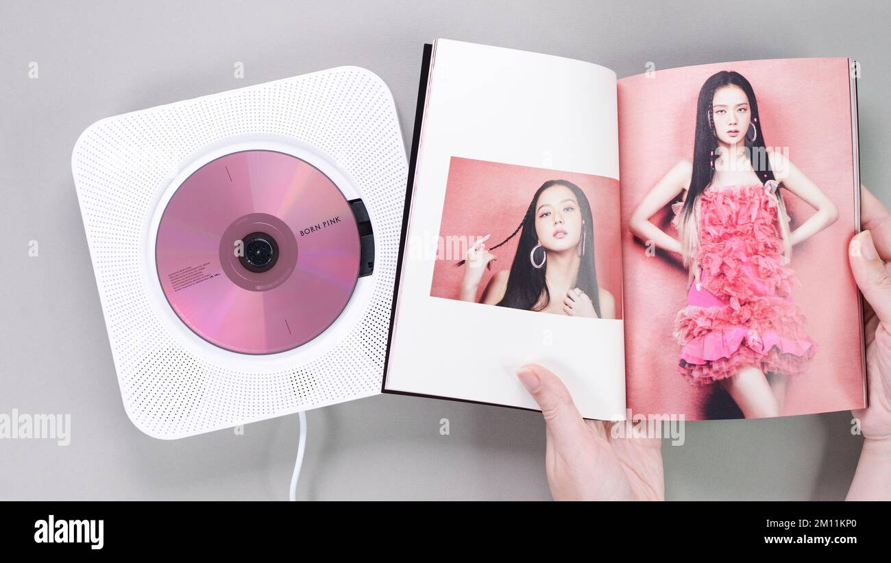 Fan hands holding BlackPink BORN PINK 2nd Album photobook with Jisoo on grey. Pink music CD in player. South Korean girl group BlackPink. Space for te Stock Photo