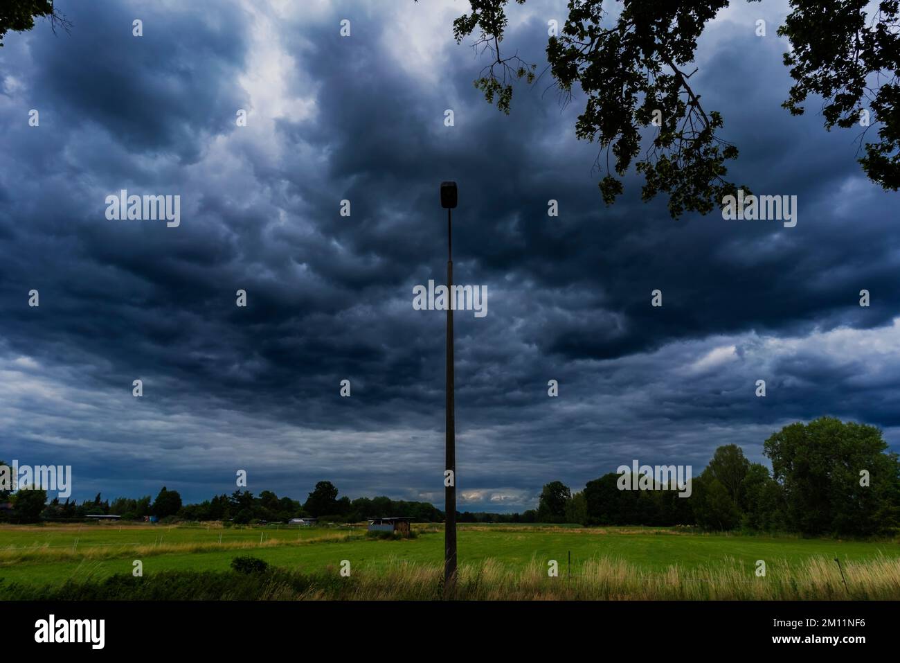 Large rain clouds shortly before a storm over a green meadow in Germany Stock Photo