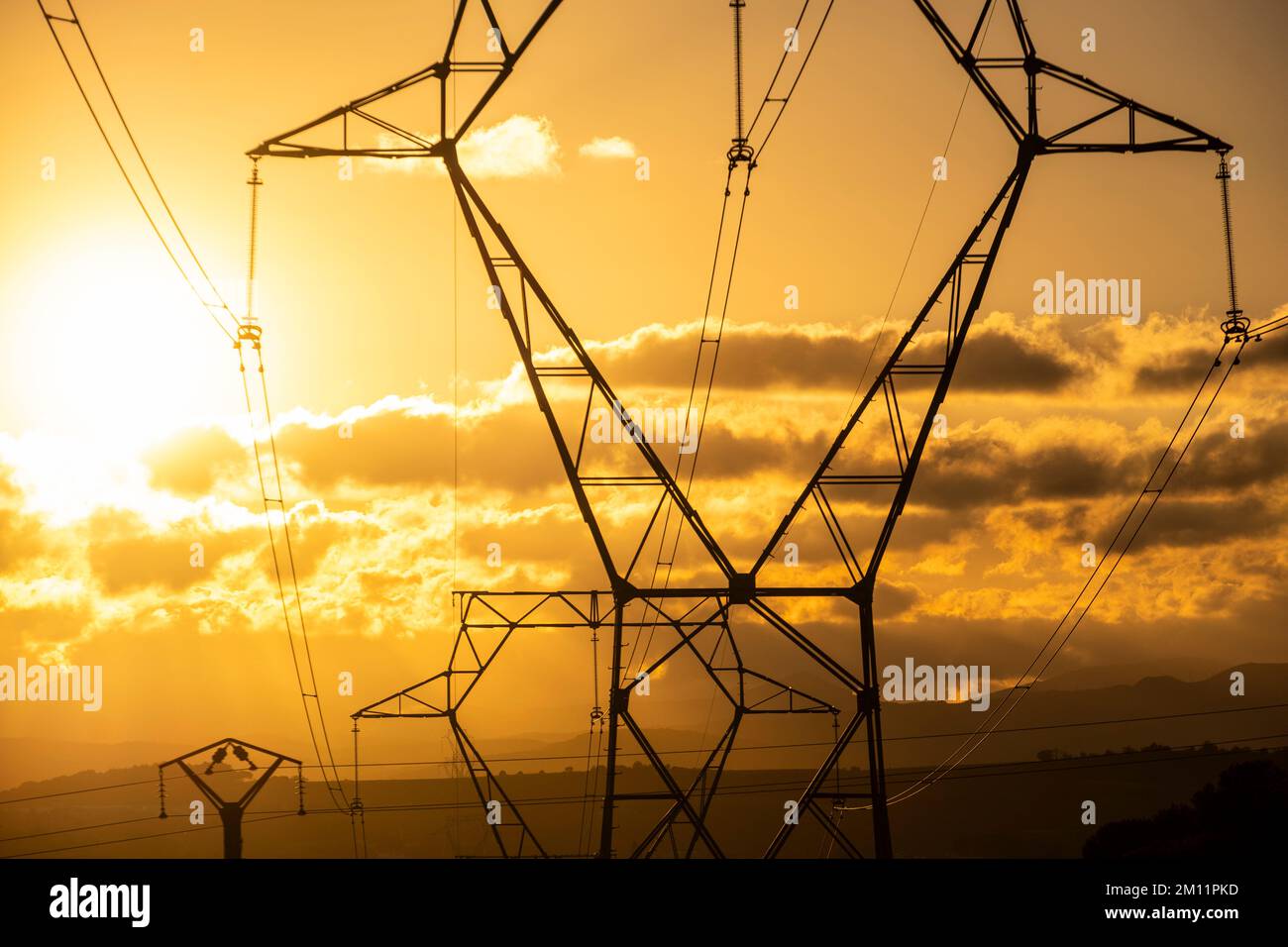 Towers of high voltage cables in an autumn sunset in the fields of the