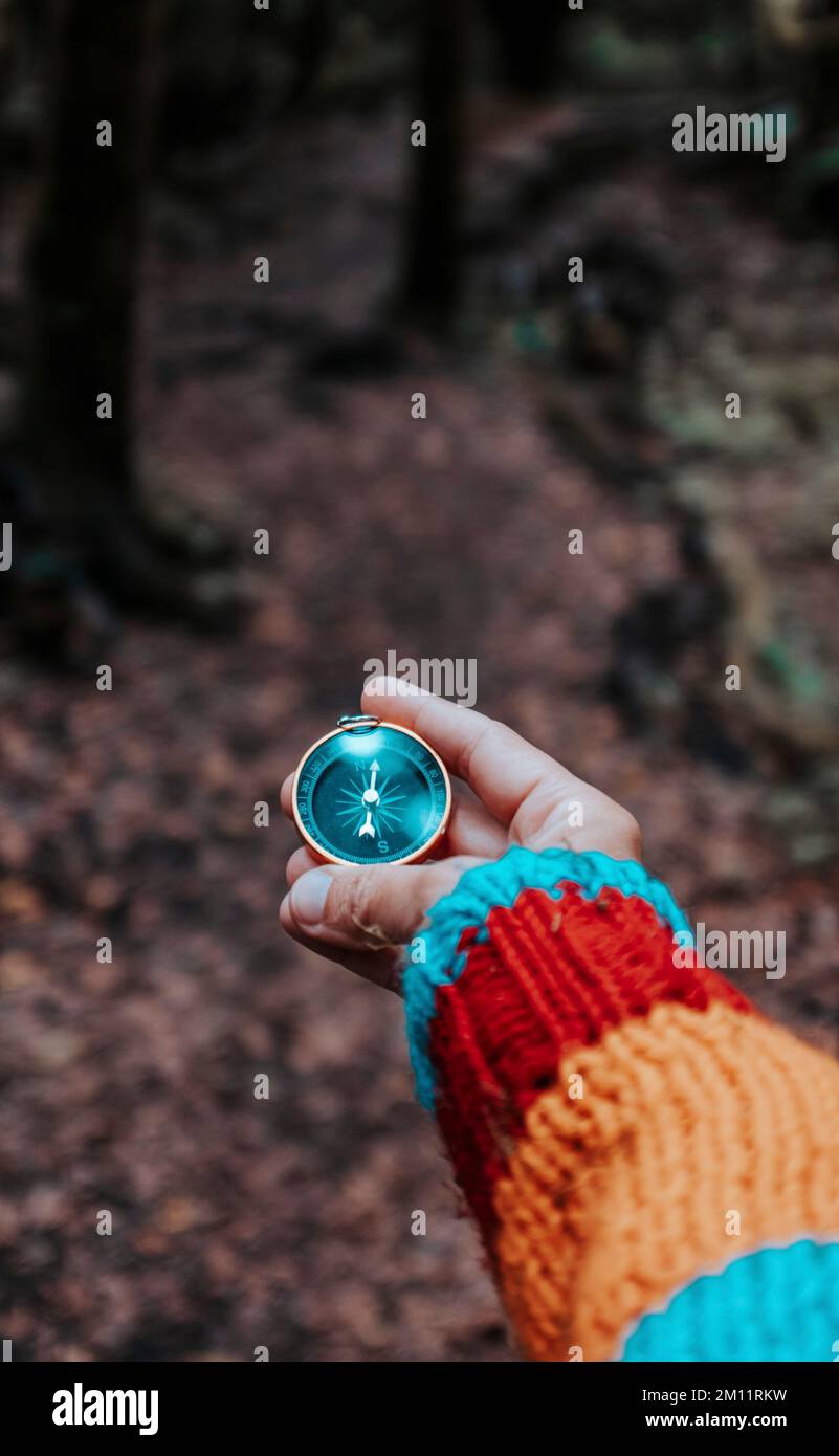 Eyes point of view pov of woman hand holding and using a magnetic old compass to find the right direction and destination. Concept looking for. People enjoy adventure in the nature forest background Stock Photo