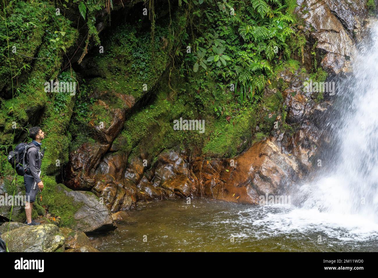 South America, Colombia, Departamento de Antioquia, Medellín, Envigado, Young man admires the waterfall Chorro de las Campanas in Quebrada la Miel Stock Photo