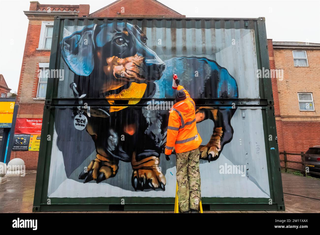 England, Dorset, Bournemouth, Boscombe, Council Worker Cleaning Street Art titled 'The Sausage Dog' by the Artist Tech Moon Stock Photo