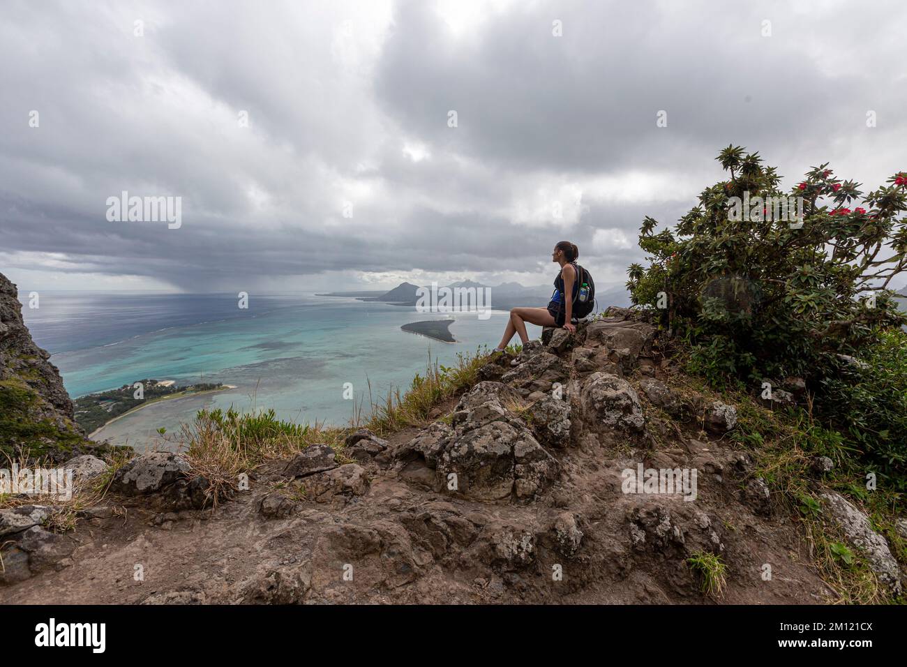 A sporty lady sitting on top of Mauritius famous mountain Le Morne Brabant mountain. Stock Photo