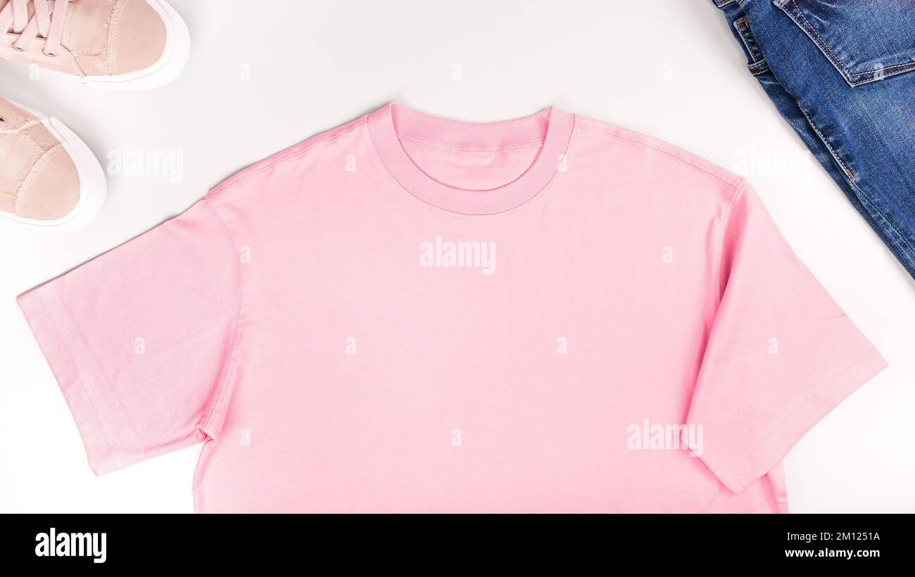 Pink unisex t shirt mock up flat lay on white background. Top front view t-shirt, snikers, jeans and copy space. Mockup tshirt tonned with popular Viv Stock Photo