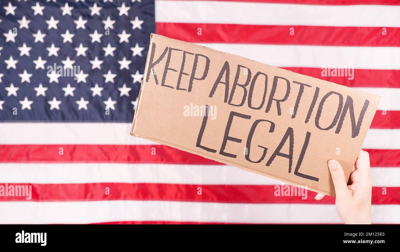 Woman is holding a sign Keep Abortion Legal USA flag on background. Protest against anti abortion law. Women's strike. Womens rights freedom Stock Photo