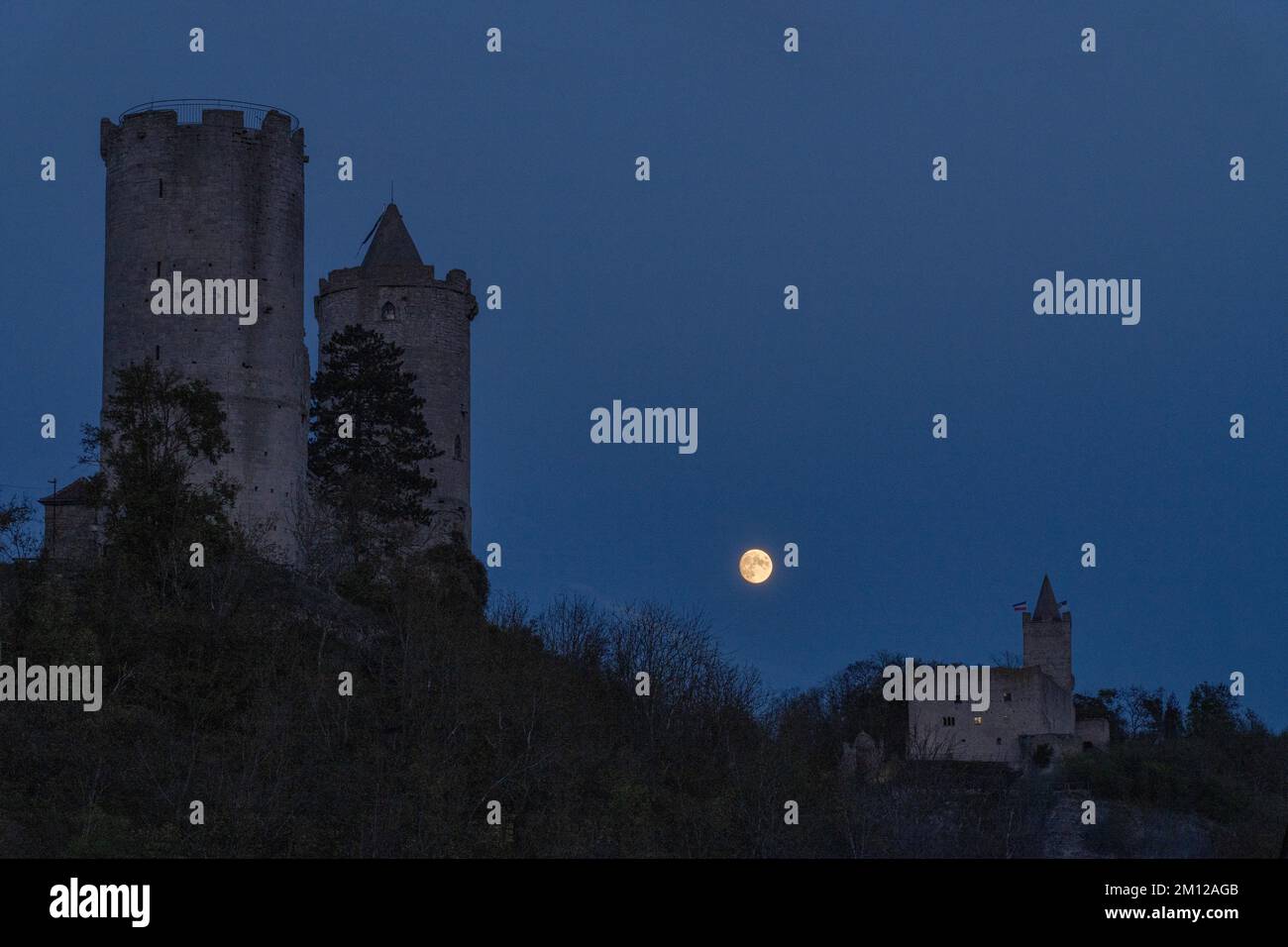 Full moon rising behind Saaleck Castle and Rudelsburg in Thuringia. Stock Photo