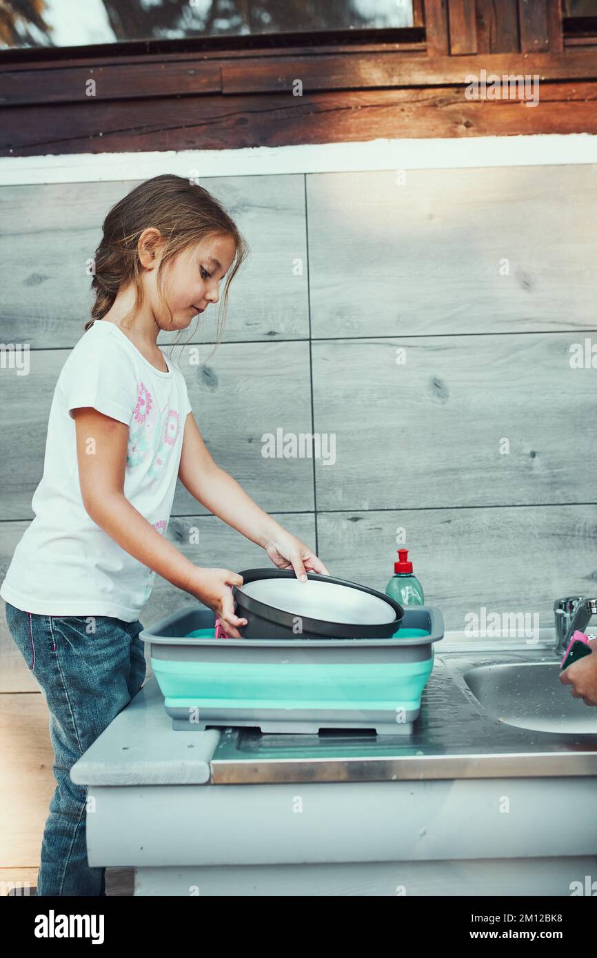 Teenager girl washing up the dishes pots and plates with help her