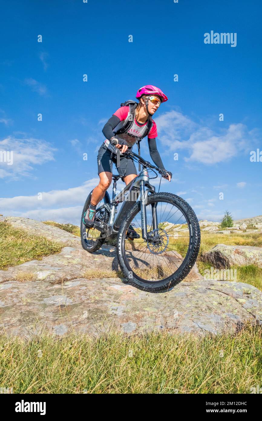 Italy, Veneto, province of Belluno, Falcade. Young girl riding an e-bike / e-mtb, free ride in the Dolomites Stock Photo