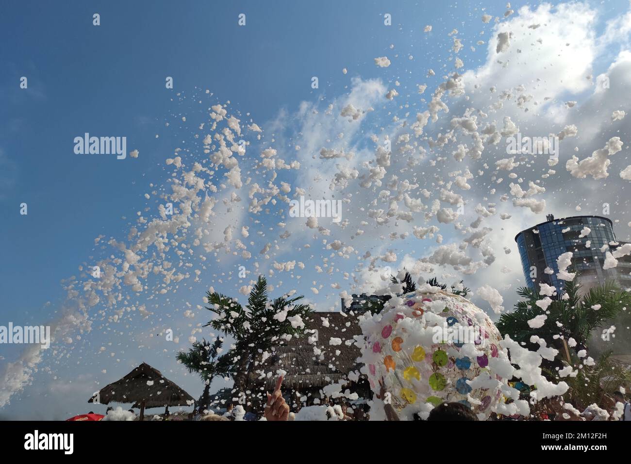 foam party on the beach, flying foam against the background of palm