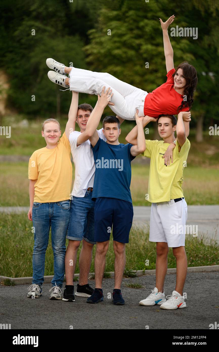 Ivano-Frankivsk, Ukraine, July 14, 2022: photo of teenagers on a sports field, four boys hold a girl in their arms, lifting her up. Stock Photo