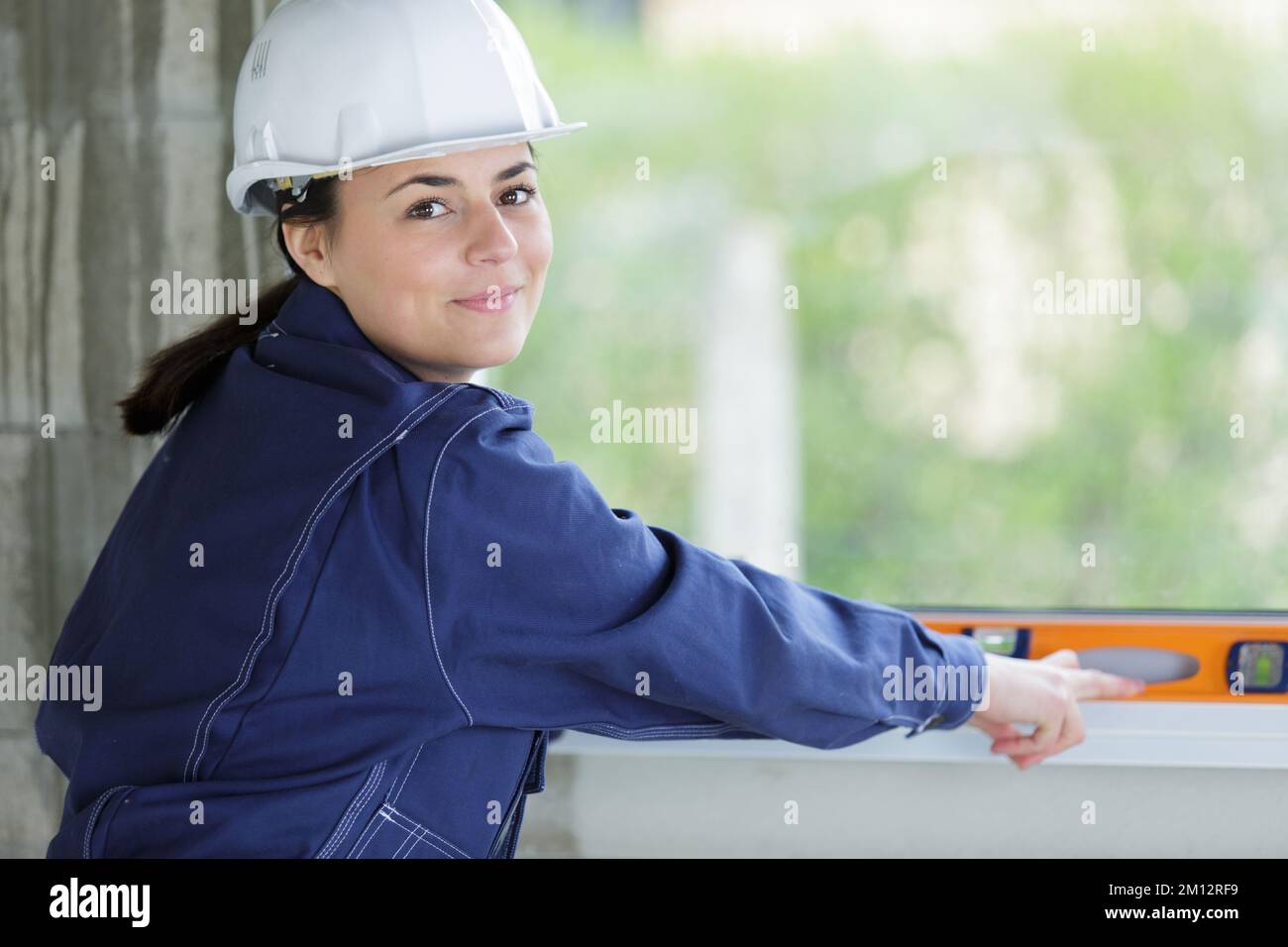 female builder using spirit level on a window Stock Photo - Alamy