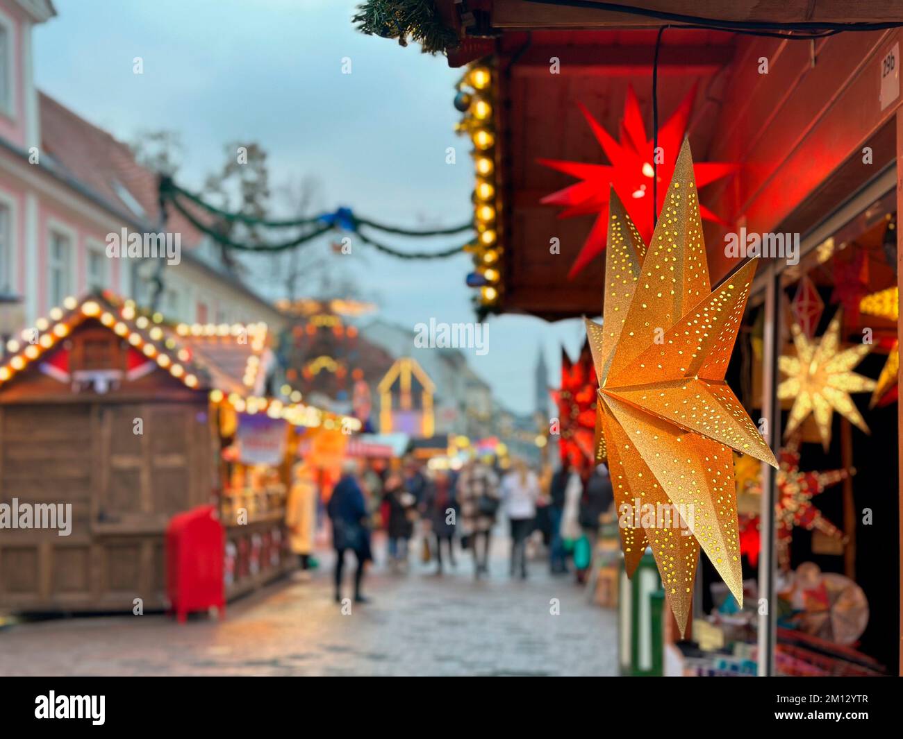 View into a pedestrian zone at pre-Christmas time with illuminated poinsettia in the foreground Stock Photo
