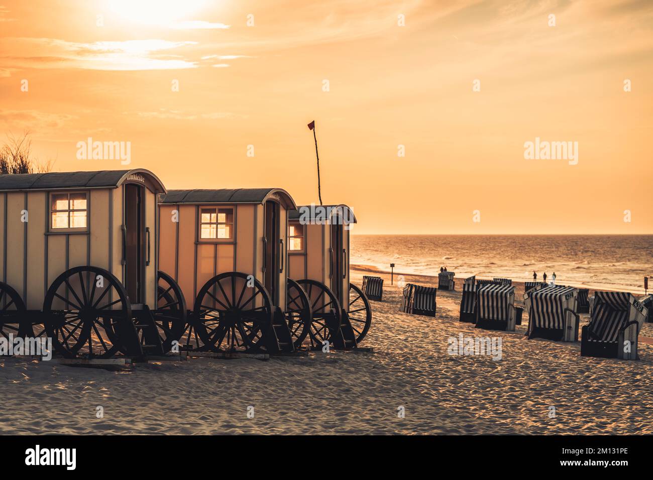 Changing rooms on the beach in the evening mood, beach chairs, in the background the North Sea, blurred people in the distance Stock Photo