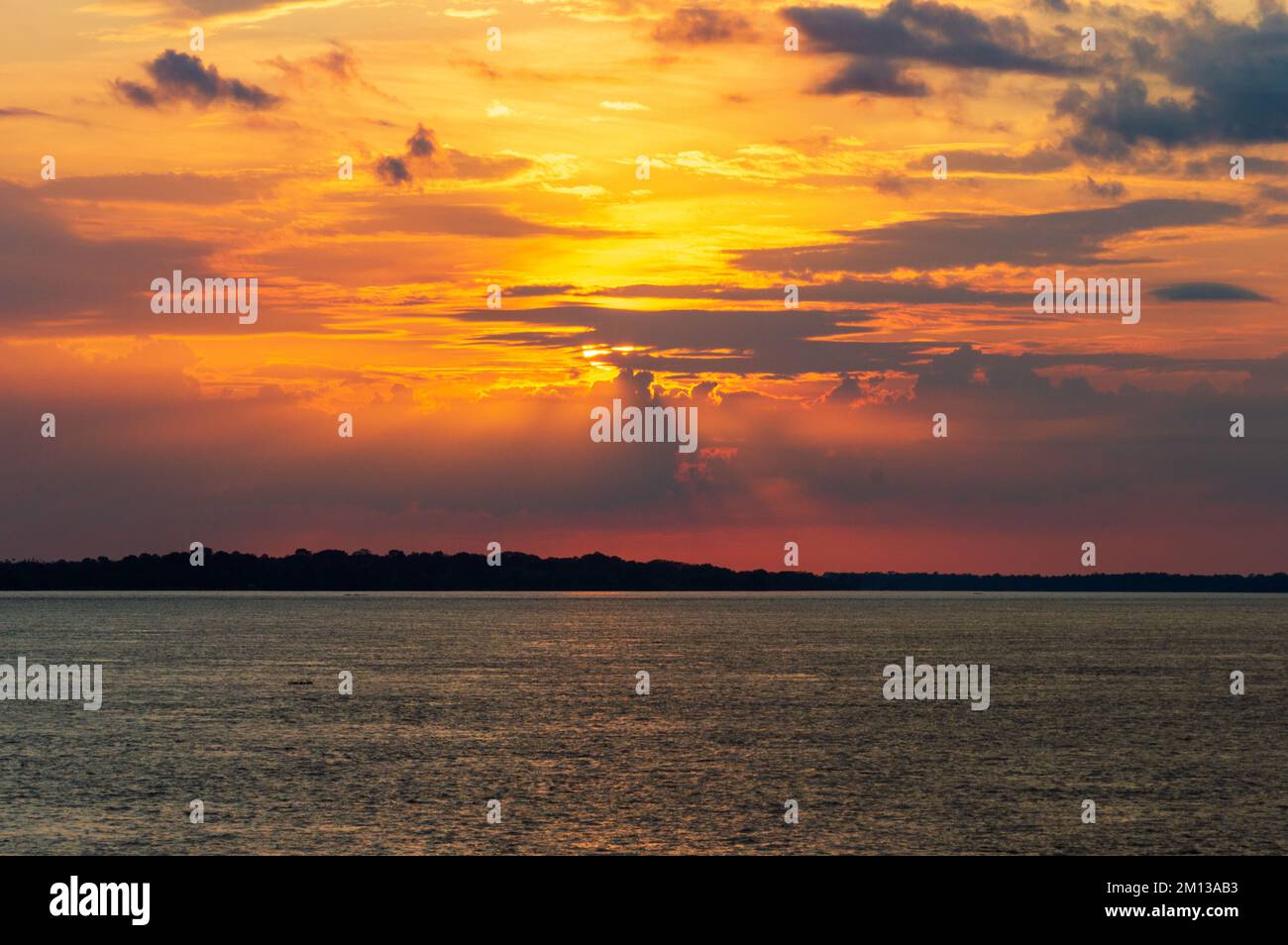 Amazing sunrise on the water of Amazon river in Brazil, nice soft warm light seeping through the clouds Stock Photo