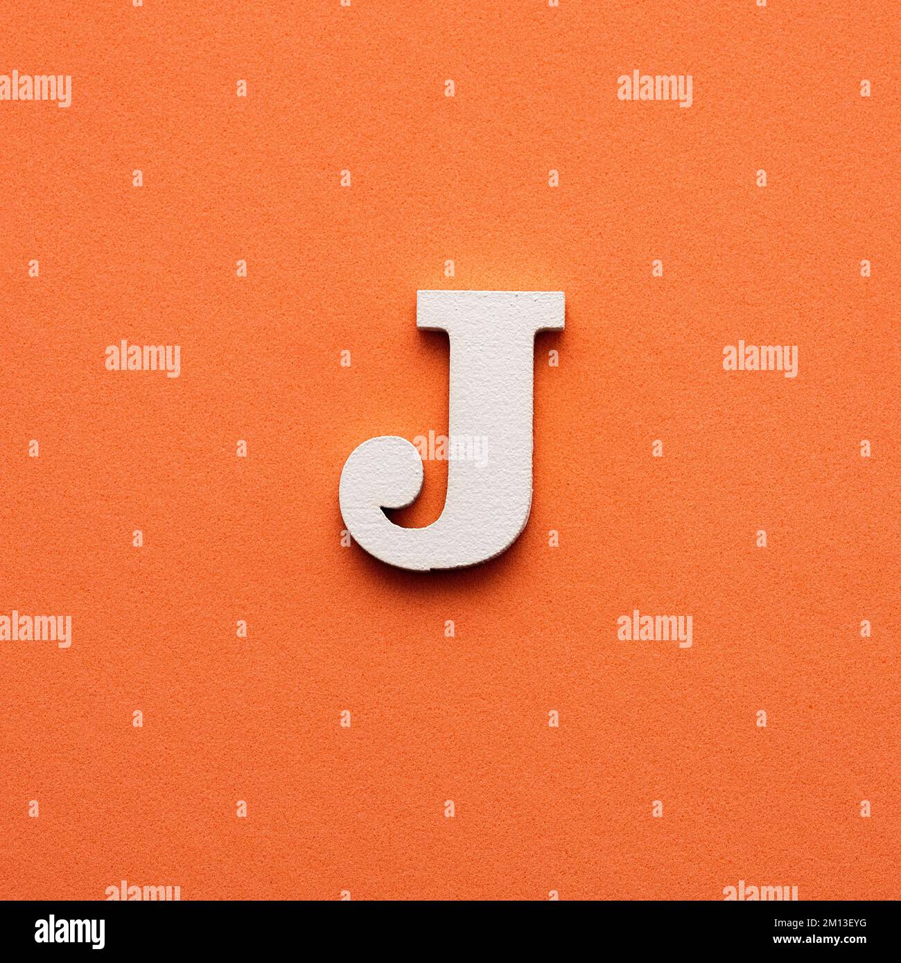 Alphabet letter J - White wooden letter on pink background Stock Photo