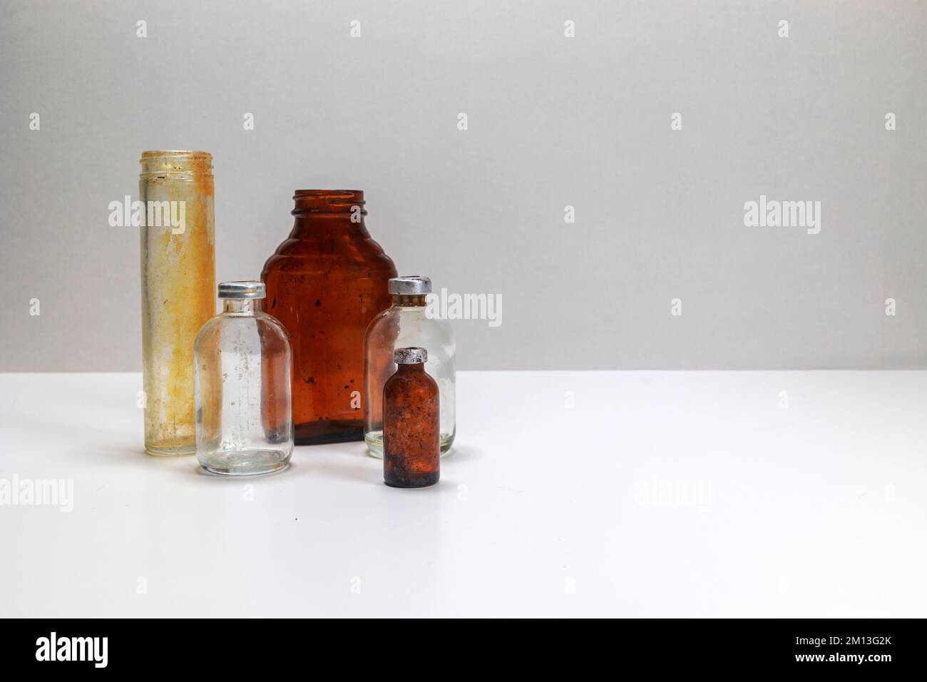 One glass test tube, one amber glass medical pill bottle, two clear glass vaccine bottles, and one small amber vaccine bottle on a white back ground. Stock Photo