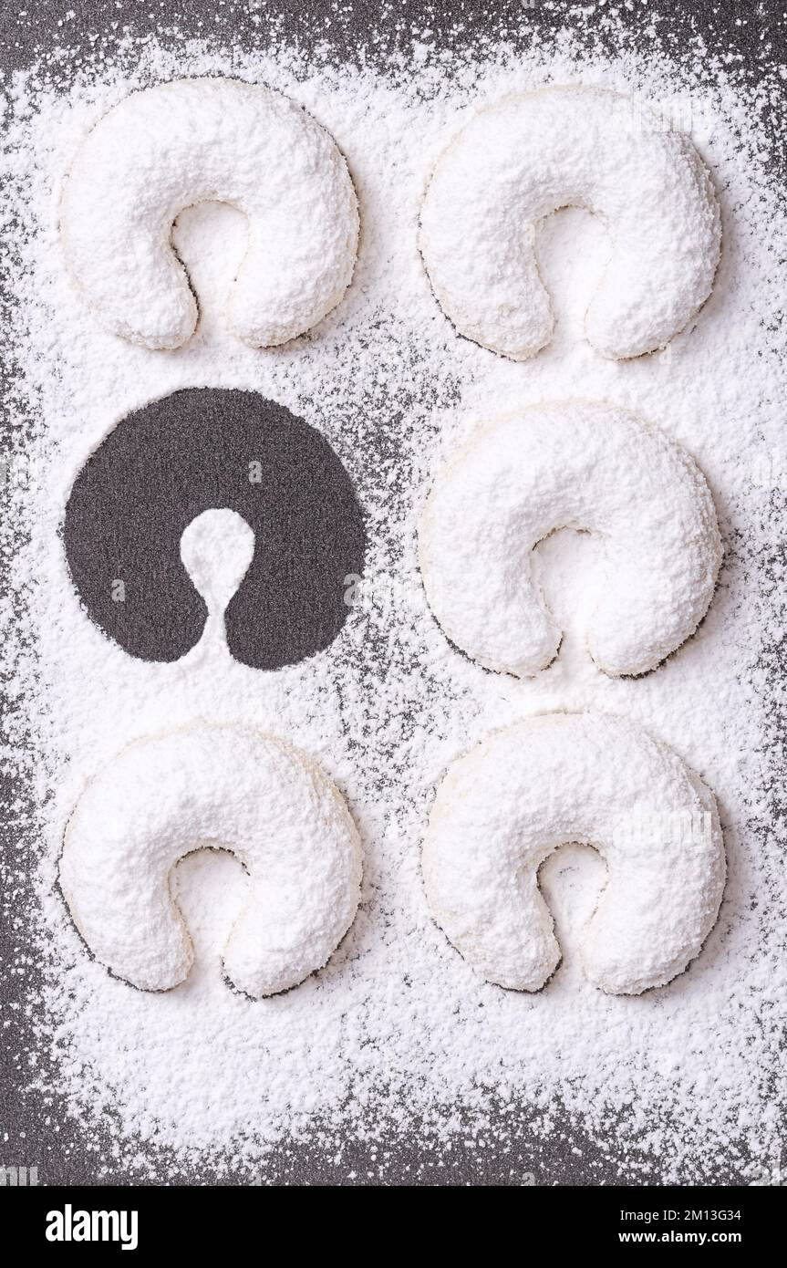 Heavy dusted vanilla crescents, with one missing on a baking tray. Vanillekipferl, crescent shaped Christmas biscuits, originally from Austria. Stock Photo