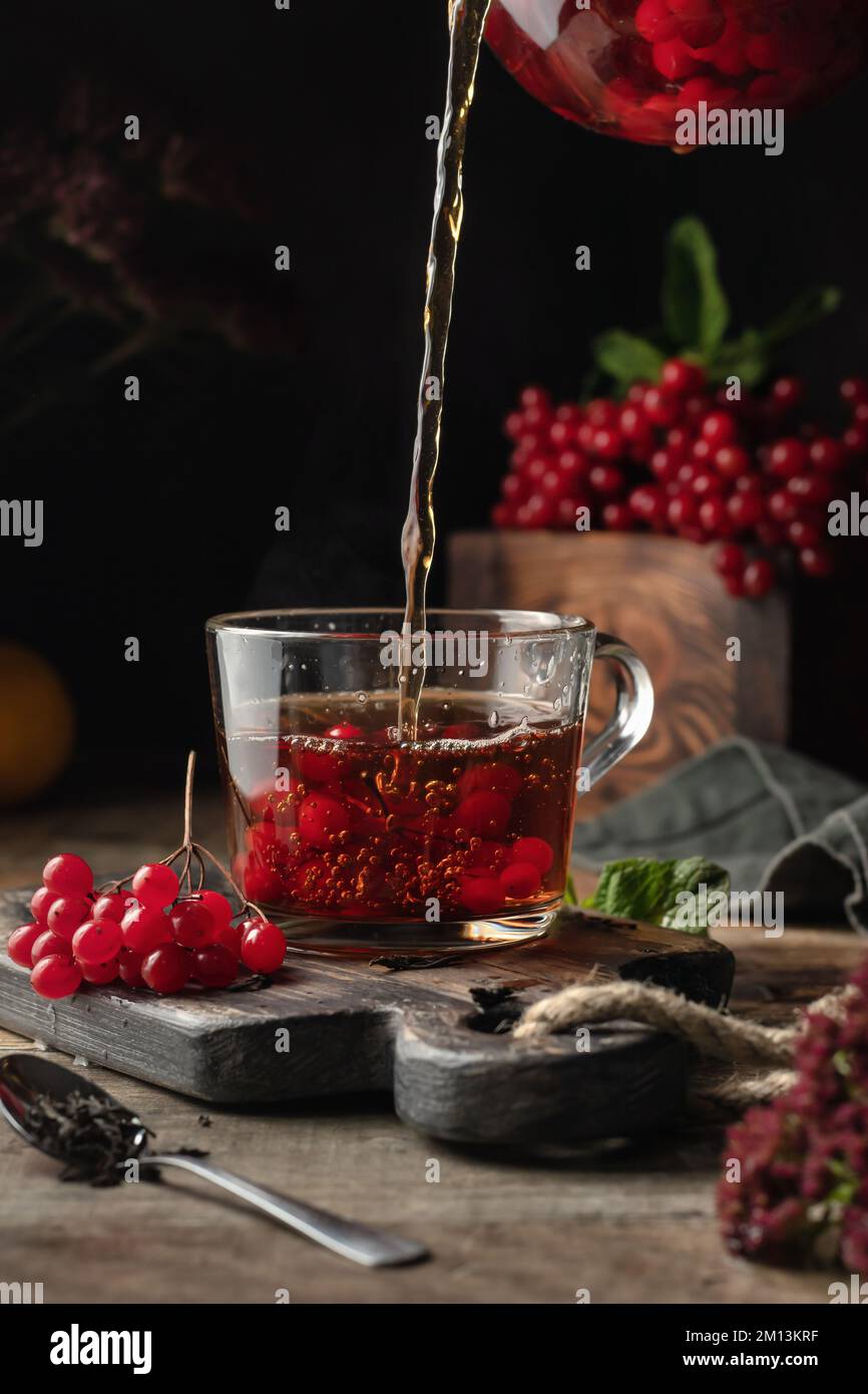 Viburnum tea is poured into a cup from a glass teapot, pouring process ...