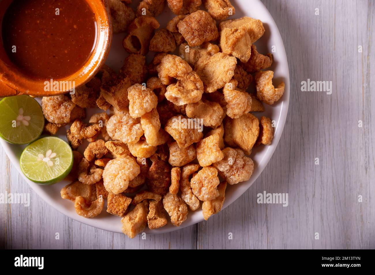 Chicharrones. Deep fried pork rinds, crispy pork skin pieces, traditional mexican ingredient or snack served with lemon juice and red hot chili sauce. Stock Photo