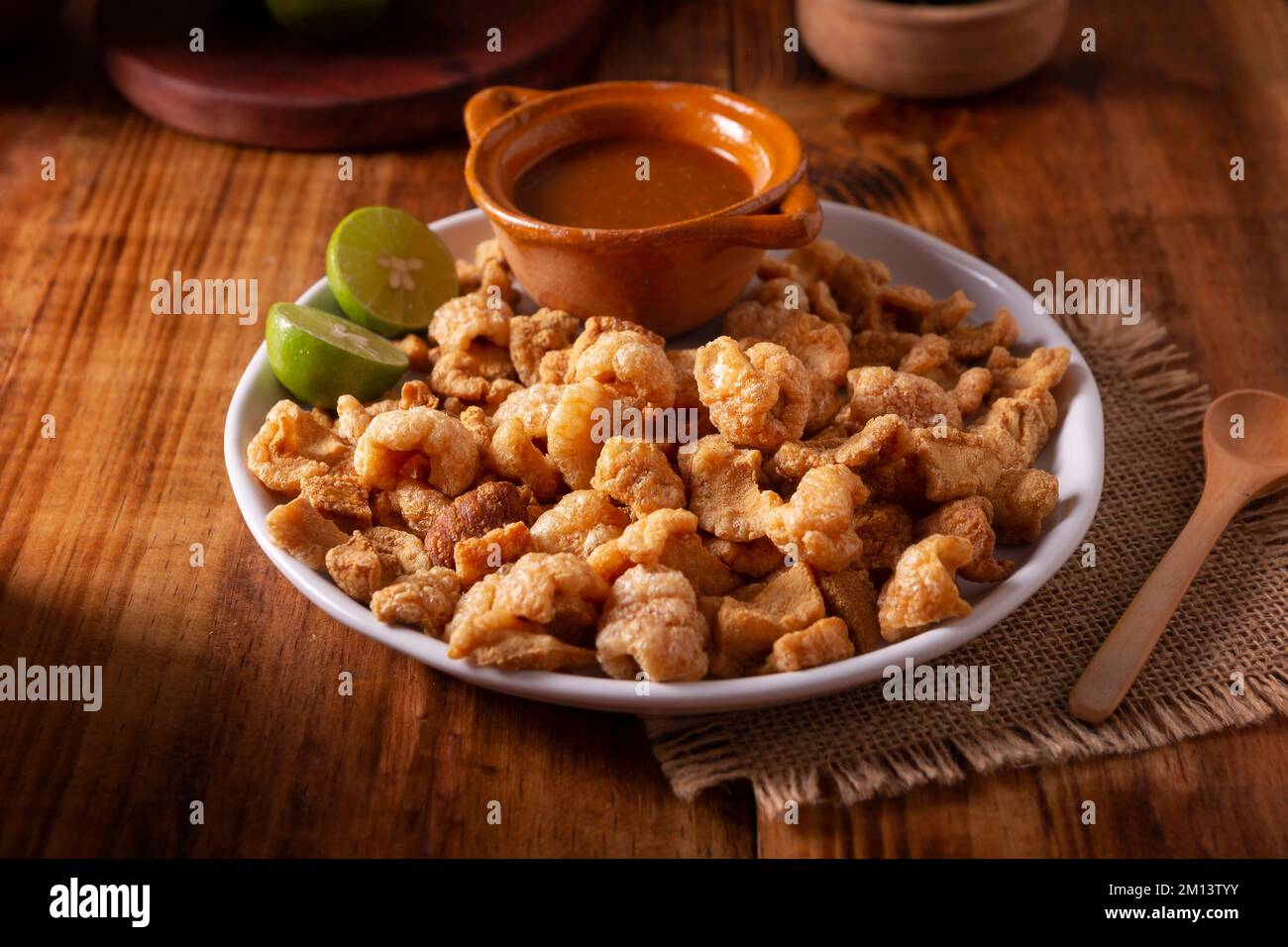 Chicharrones. Deep fried pork rinds, crispy pork skin pieces, traditional mexican ingredient or snack served with lemon juice and red hot chili sauce. Stock Photo
