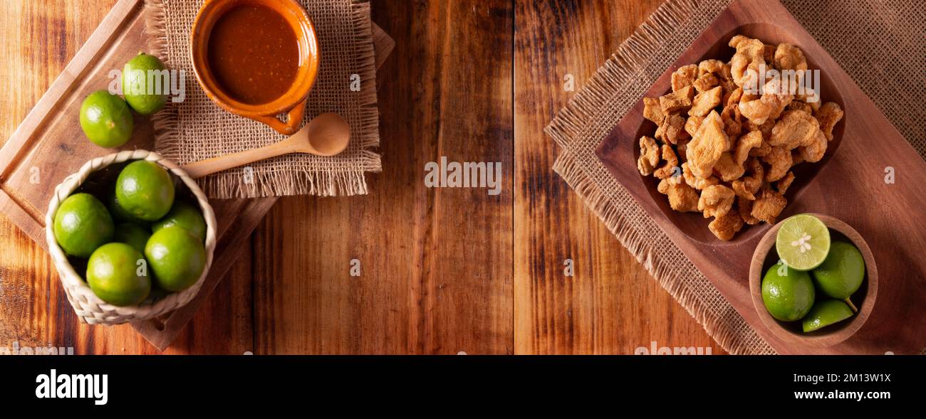 Chicharrones. Deep fried pork rinds, crispy pork skin pieces, traditional mexican ingredient or snack served with lemon juice and red hot chili sauce. Stock Photo