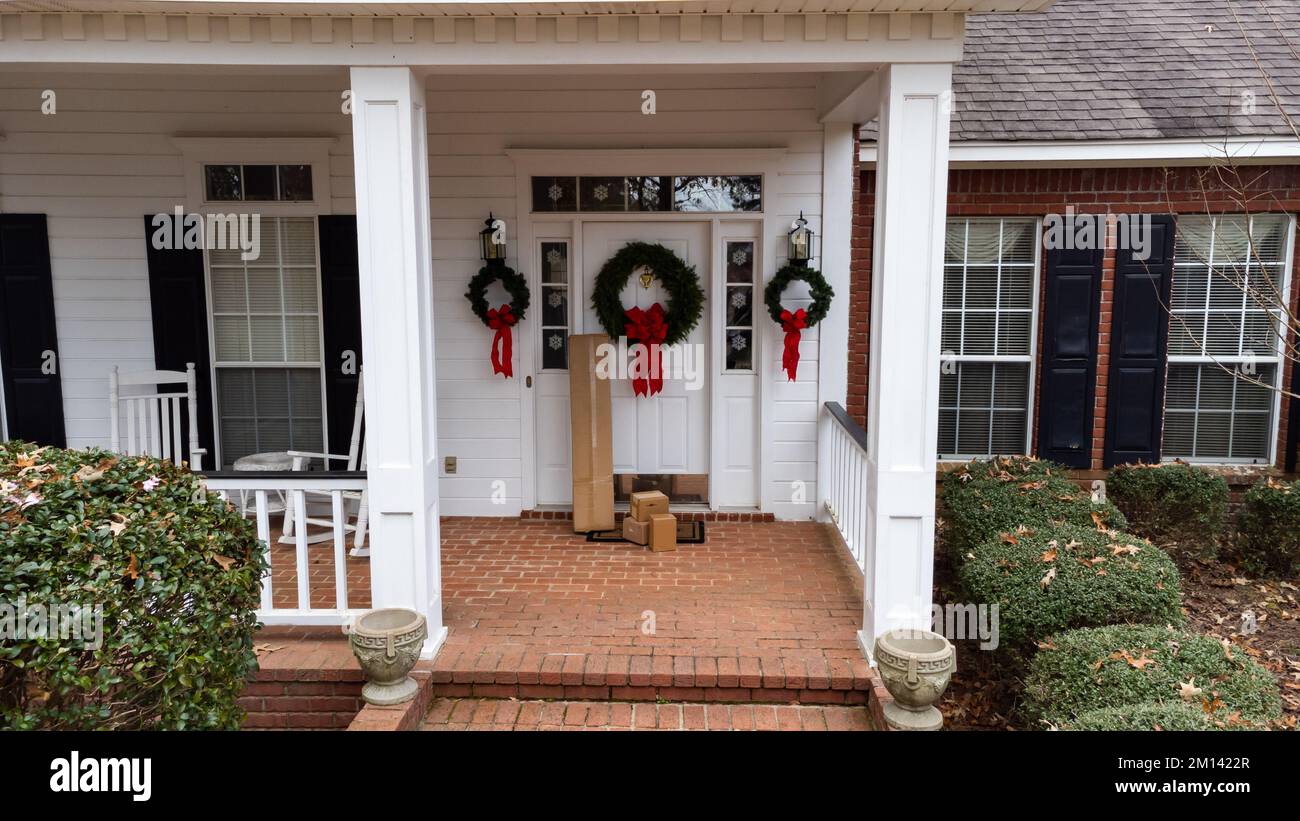 Shipping boxes near front door of home decorated for the holidays. Stock Photo