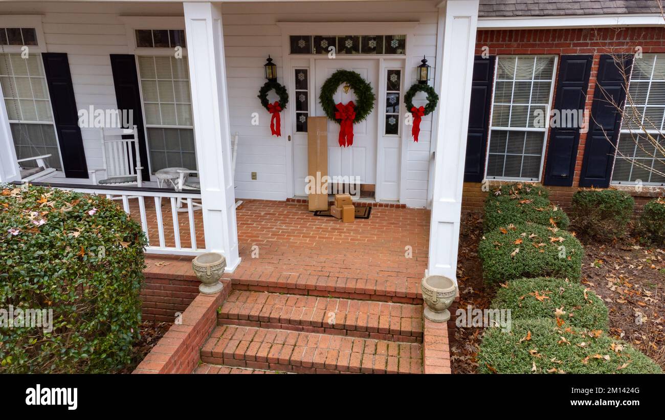 Shipping boxes near front door of home decorated for the holidays. Stock Photo