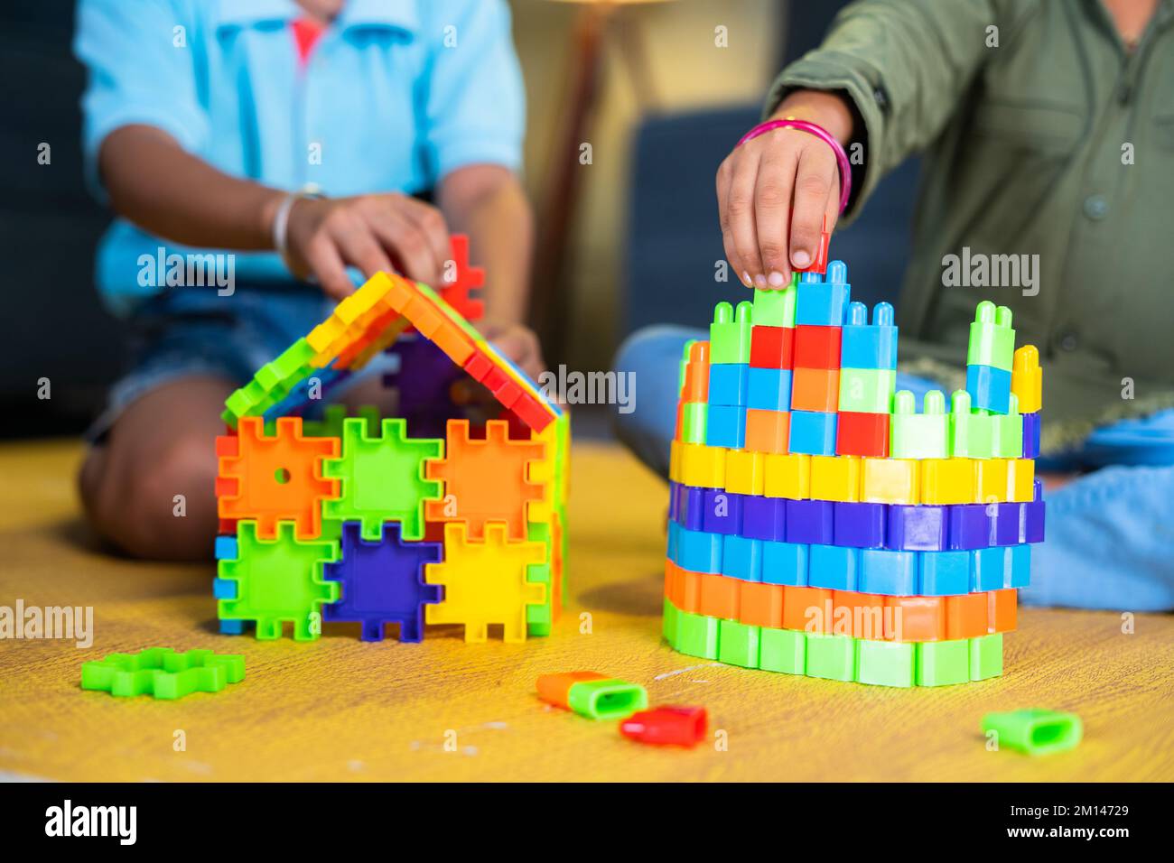 Close up shot of siblings kids playing with toys building blocks while sitting at home - concept of entertainment, togetherness and development Stock Photo