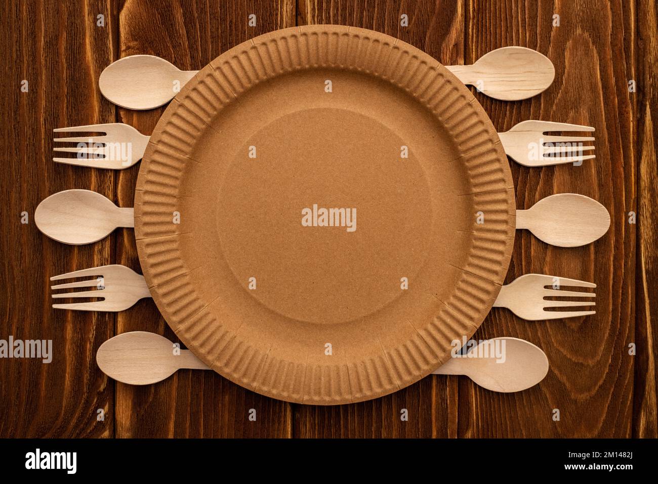 Wooden forks and spoons and paper plate on wooden background Stock Photo