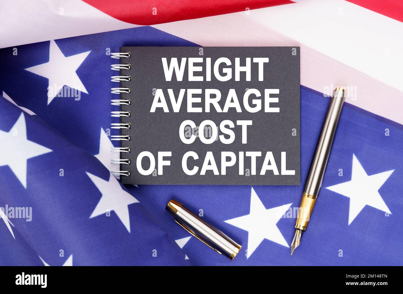 Business and finance concept. On the table is an American flag, a pen and a notebook with the inscription - WEIGHT AVERAGE COST OF CAPITAL Stock Photo