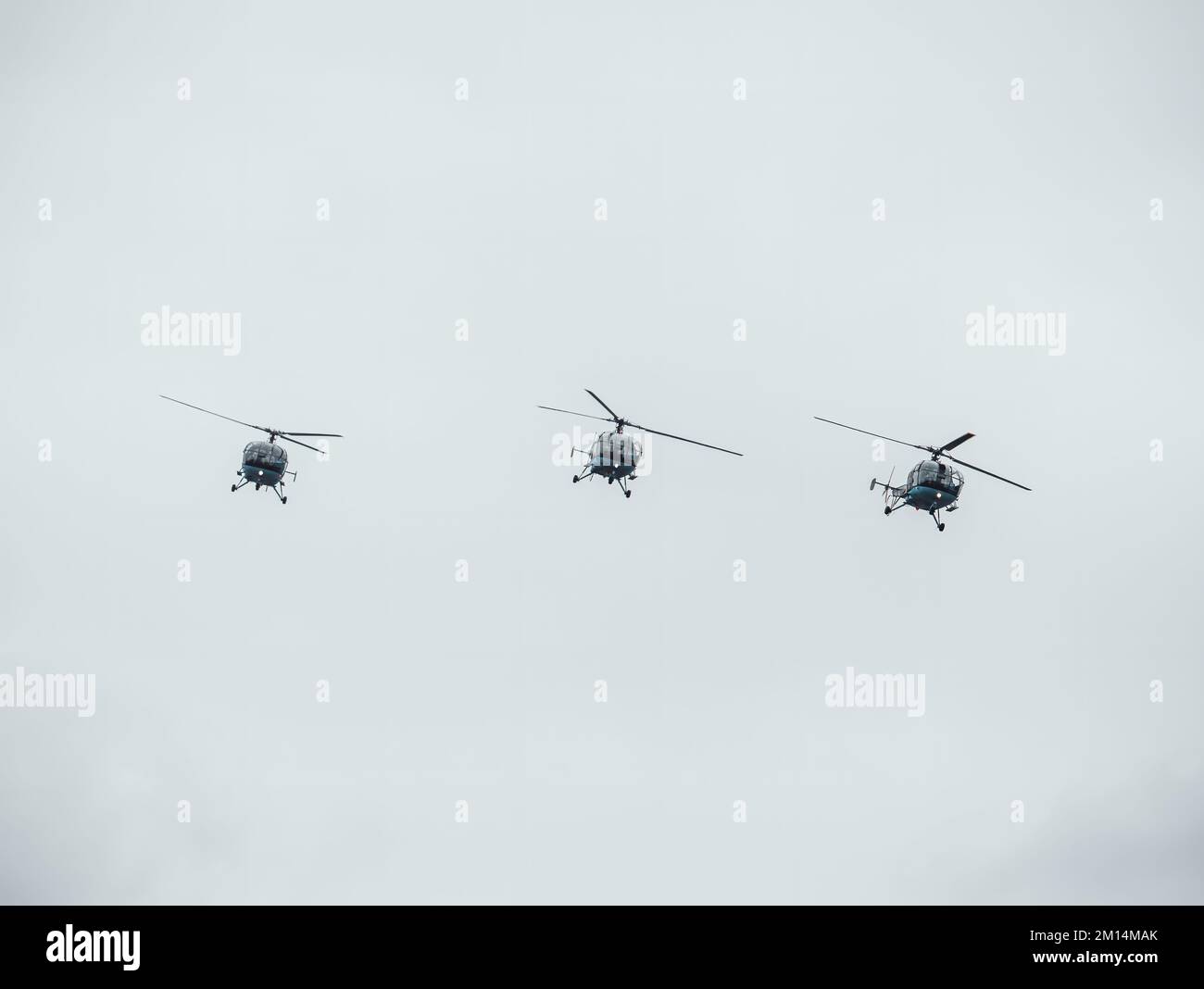 Three helicopters flying against a cloudy sky. Airshow demonstration. Stock Photo