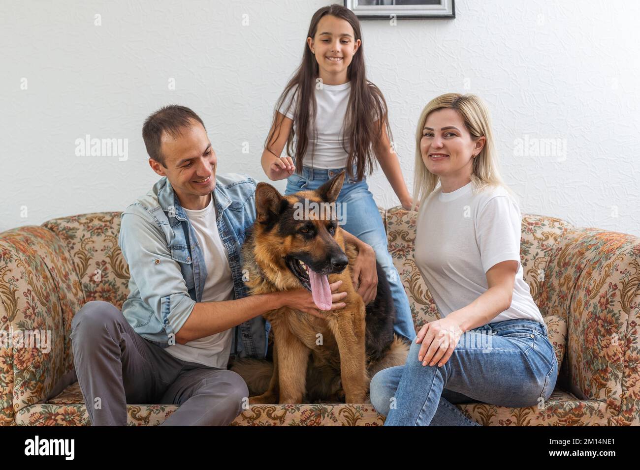 Mom, dad, and daughter having fun playing with big dog Stock Photo - Alamy