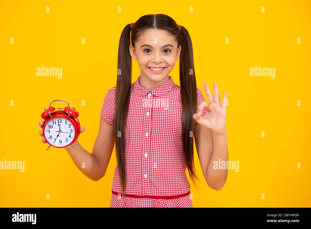 Child 12, 13, 14 years old look at alarm clock. Time for shopping sales. Good morning, checking time. Happy teenager, positive and smiling emotions of Stock Photo