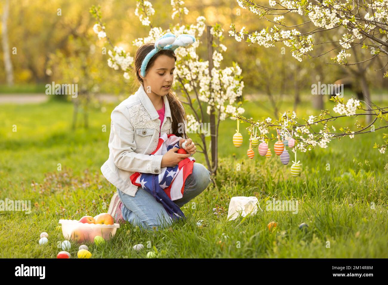 A teenage girl in a blooming garden at Easter with a US flag Stock ...
