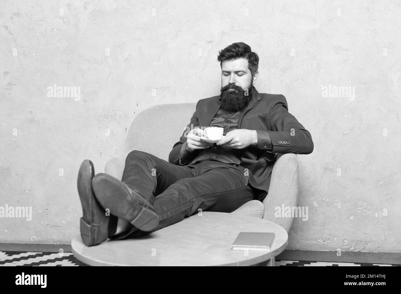 Relaxing guy employee drink tea sitting feet up in rest armchair, tea