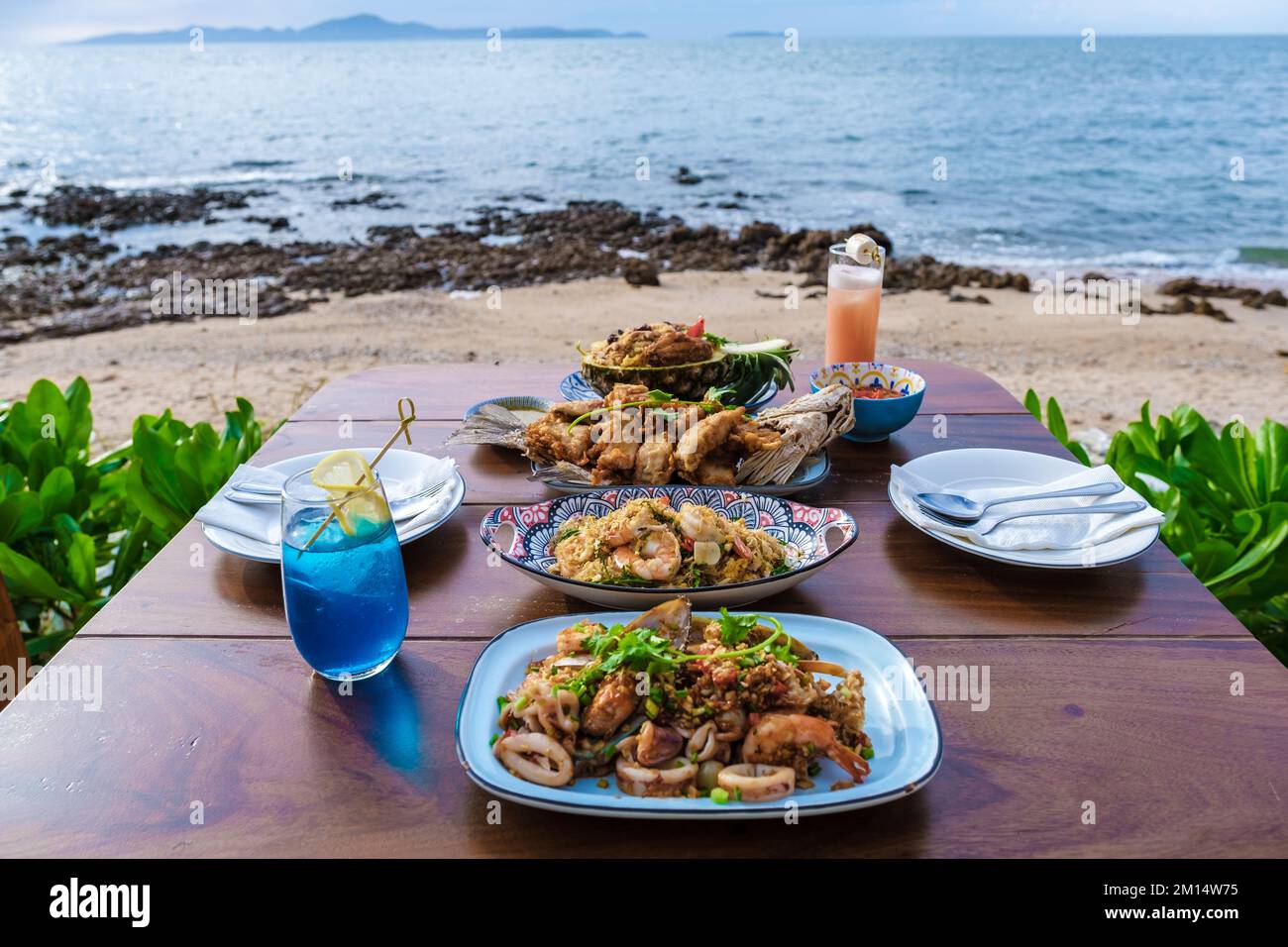 Dinner table with Thai food and bbq fish on the beach of Pattaya
