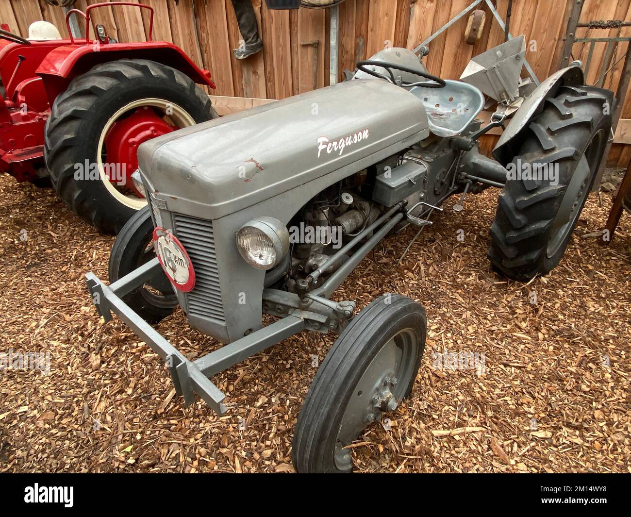 The old agricultural gray Ferguson tractor parked over the woodchips in a barn Stock Photo