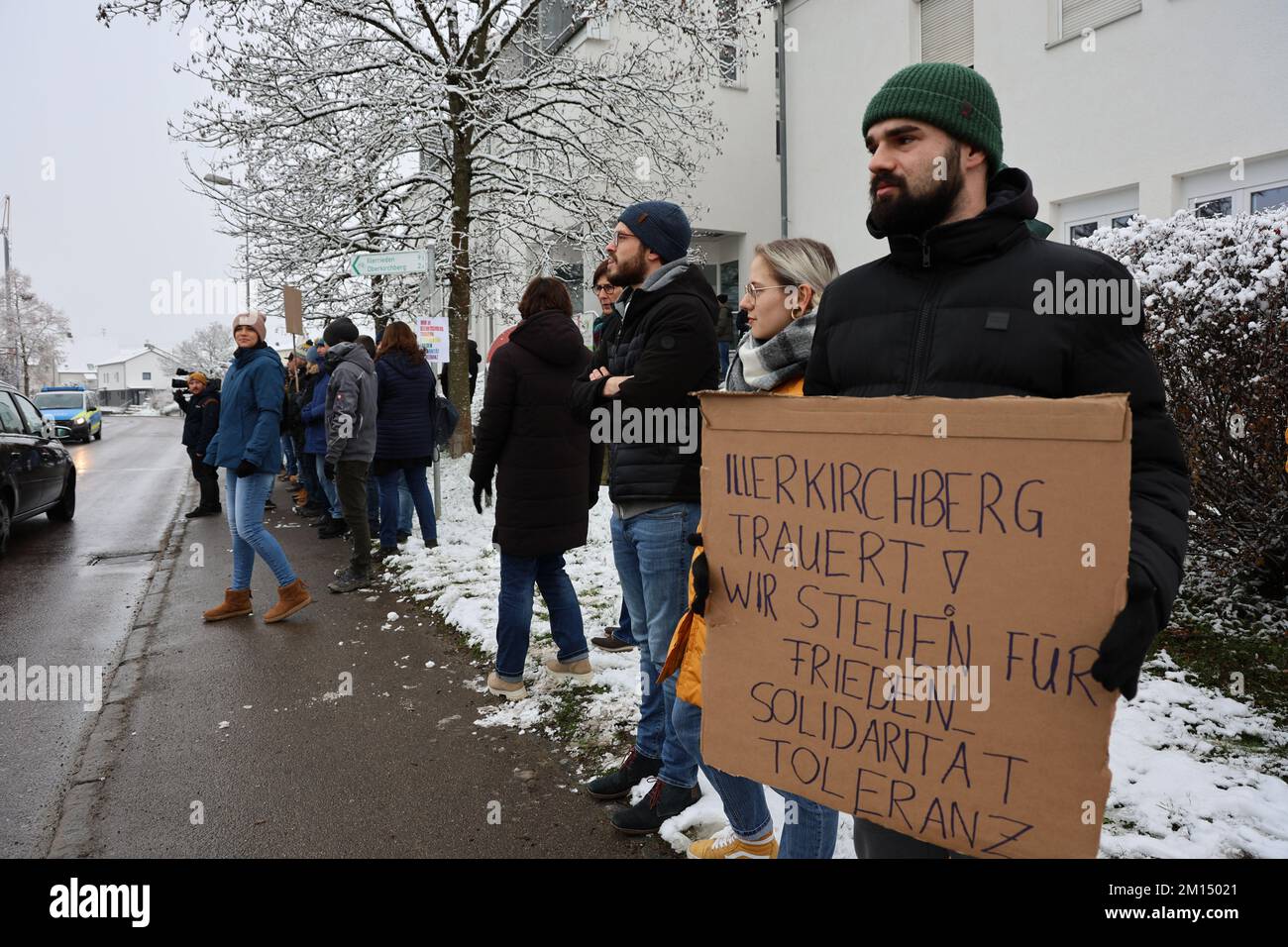 Illerkirchberg, Germany. 10th Dec, 2022. People stand at a spontaneous gathering for tolerance and against the AfD rally near the town hall square, where the AfD rally is taking place. A man carries a sign with the inscription 'Illerkirchberg mourns We stand for peace Solidarity Tolerance'. The AfD held a rally after the violent crime against two girls in Illerkirchberg near Ulm on Saturday. Credit: Ralf Zwiebler/dpa/Alamy Live News Stock Photo
