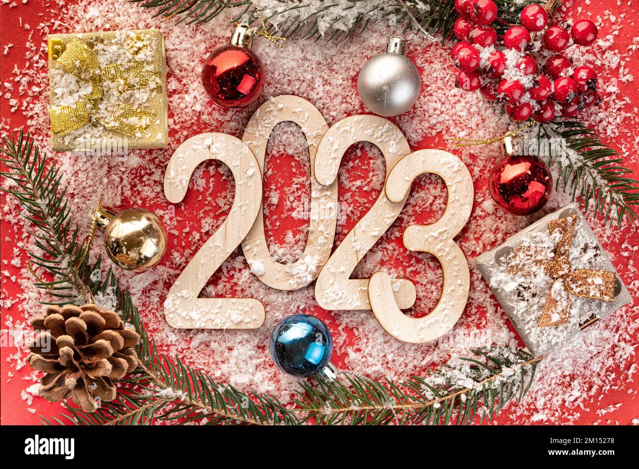 New Year's number 2023 made of wooden numbers on red paper with Christmas balls, gift boxes, fir branches Stock Photo