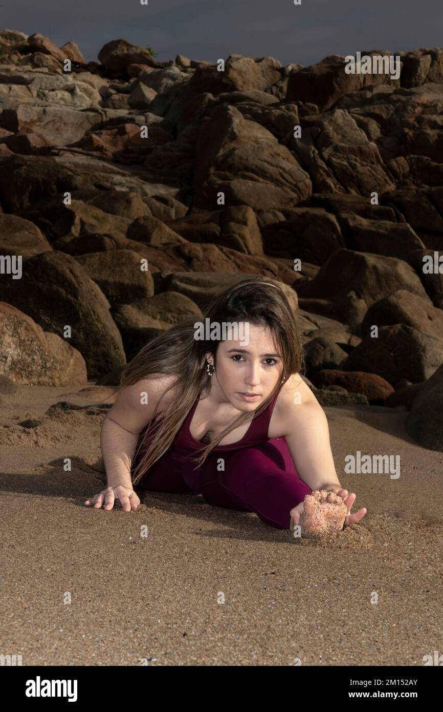 a young woman, who practices yoga, does a stretching exercise on the beach. split woman Stock Photo