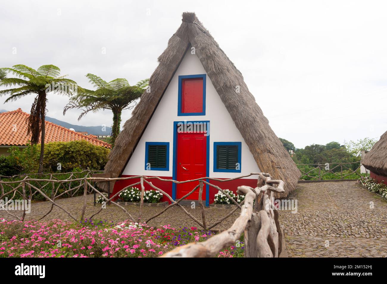 A typical small triangular house in Santana surrounded by beautiful gardens in Madeira Stock Photo