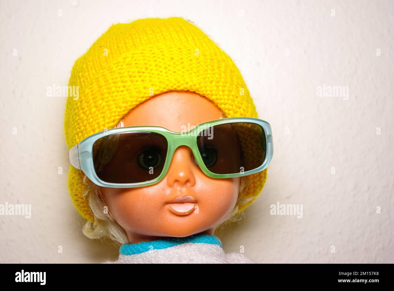 Smart doll with sunglasses and yellow knitted cap, children's toy from the GDR of the 1970s, concept of childlike play and human expression. Stock Photo