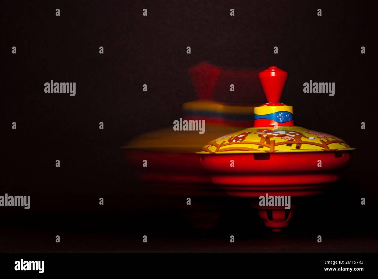 Spinning and moving humming top against a black background, concept of toddler play and toys. Stock Photo